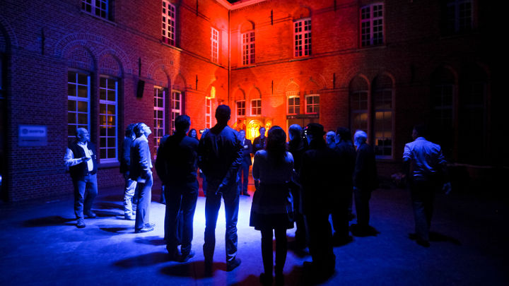 フィリップスが主催したワープショップでは、ベルギーのトゥルンハウトにある美しく照明されたビルの外で多くの参加者が話し合っています