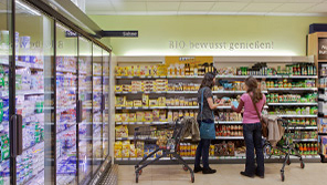 フィリップスの照明がウィーン (オーストリア) のスーパーマーケット、スパーで人々を温かく迎え入れる雰囲気を作り出す    2 人の女性がオーバーハウゼン (ドイツ) のスーパーマーケット、カイザーステンゲルマンで、フィリップスの照明の下、買い物をしている